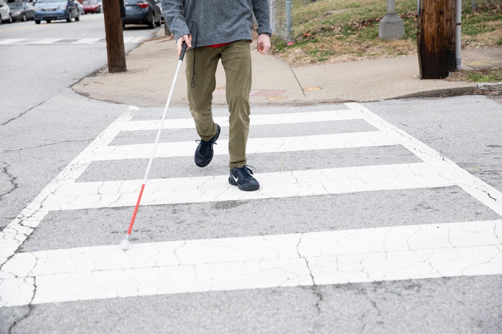 Pessoa utilizando bengala branca ao atravessar uma faixa de pedestres; fotografia ilustrativa, sem relação com o evento em Boston.